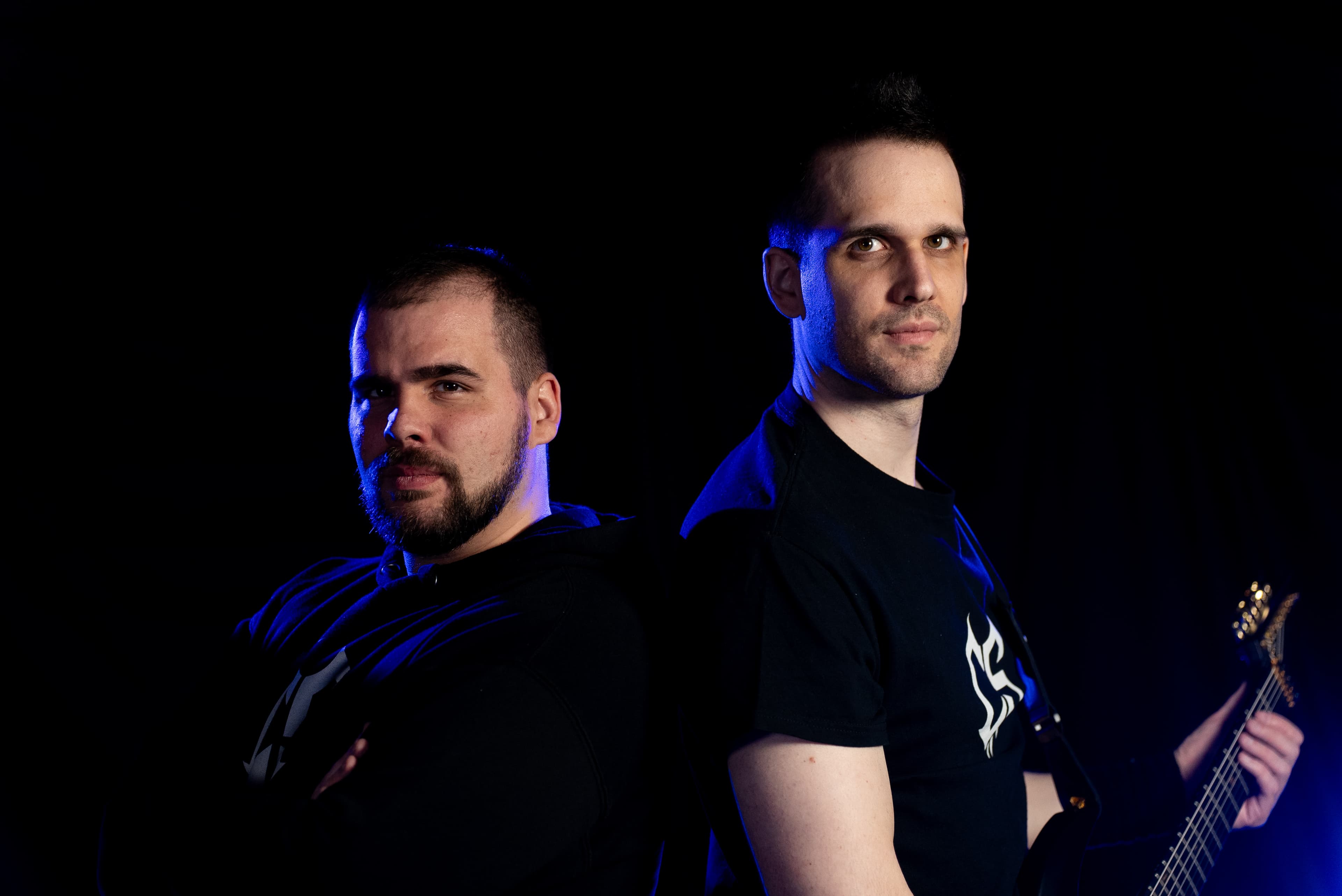 Two brothers together in a dark studio-style music portrait.