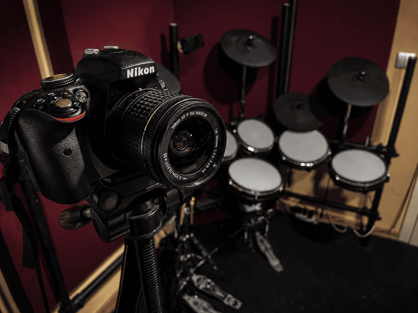 A camera set up beside an electronic drum kit in a music studio.